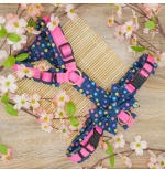 Ein Geschirre mit blauem Stoff und bunten Punkten aus Softshell. Das Geschirr hat pinkes Gurtband. Das Geschirr ist mit Acetal Schnalle und -schiebern ausgestattet und mit Messing-Ringe. An dem Geschirr ist noch eine Fliege aus dem gleichen Stoff wie das Geschirr befestigt. Der Stoff heißt Konpeitō