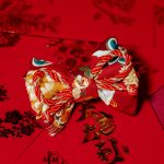 Rote Fliege mit Pferdemuster und mit roter Glückskordel auf roten chinesischen Geldumschlägen namens Hong Bao