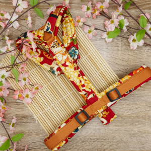 TsukiAshi Baumwoll Y-Geschirr aus einem roten Stoff mit ummantelten Rückensteg, Brussteg und Schulterpolster. Die Metalle sind aus Acetal und Messing.